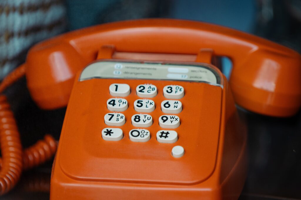 Close-up of a classic orange rotary telephone, showcasing retro design details.